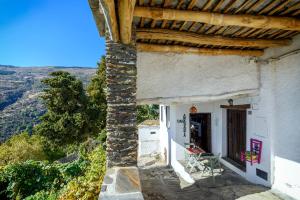 ein weißes Haus mit einem Tisch und Stühlen auf der Veranda in der Unterkunft Casa Amaranta in Capileira