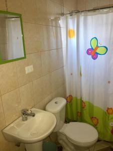 a bathroom with a toilet and a sink and a shower curtain at Cabañas a Cuadras Laguna Quillón in Quillón