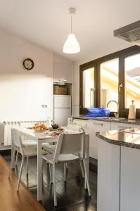 uma cozinha com armários brancos e uma mesa e cadeiras em Ático Lobariñas em Allariz