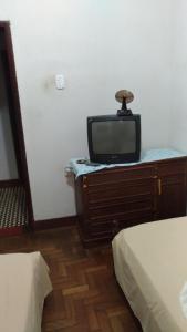 un televisor sentado en la parte superior de un tocador en un dormitorio en Hotel Indaiá en Governador Valadares