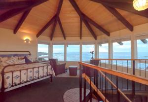 a bedroom with a bed in a room with windows at Cliff House at Otter Point in Mendocino