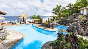 阿洛菲的住宿－瑪塔凡紐埃美景度假村，一个带椅子的游泳池,背景是大海