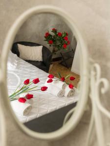 ローマにあるNapoleone Holiday Apartmentの鏡に赤いバラが映るベッド