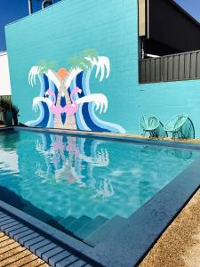 a swimming pool with a mural on the side of a building at Cascades Motor Inn in Dubbo