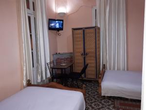Cette chambre comprend deux lits, une table et une télévision. dans l'établissement Pension Safari, à Tanger