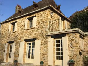Gîte Le Recoux في Mouzens: منزل حجري قديم بأبواب ونوافذ بيضاء