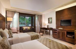 a hotel room with two beds and a flat screen tv at Ubud Village Hotel in Ubud