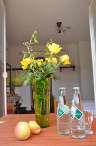 una mesa con dos botellas y un jarrón con flores amarillas en Pension Stissen Haus am See, en Faak am See