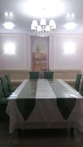 uma sala de jantar com uma mesa longa e cadeiras verdes em Semey Hotel em Semei