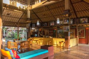 um restaurante com um bar com mesas e cadeiras em Puri Taman Sari em Tabanan