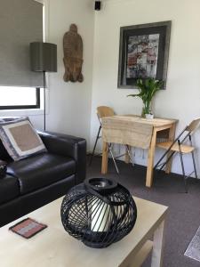 een woonkamer met een zwarte bank en een tafel bij Nextdoor@portarthur in Port Arthur