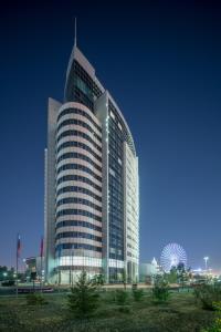 a tall building with a ferris wheel in front of it at Hotel Duman in Astana