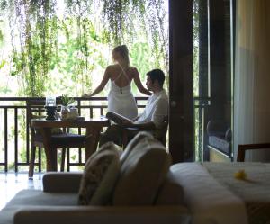 a man and a woman sitting at a table on a porch at Ubud Village Hotel in Ubud