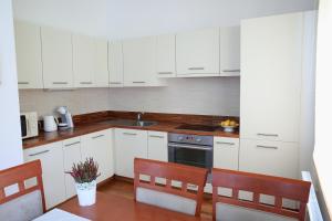 uma cozinha com armários brancos e uma mesa com cadeiras em Apartman Bellevue em Spindleruv Mlyn
