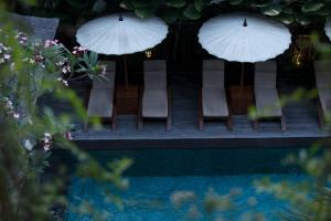 a group of chairs and umbrellas next to a pool at Ubud Village Hotel in Ubud