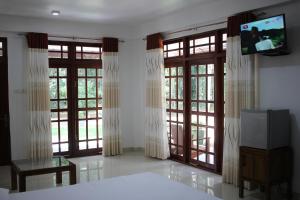 a bedroom with doors and windows with a tv on the wall at Gem Field Rest in Ratnapura