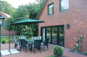 a table with chairs and an umbrella in front of a brick building at Bernard Meyborg in Lindern