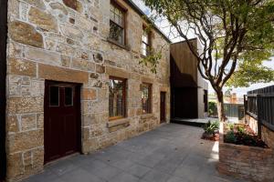 un bâtiment en briques avec une porte et un arbre dans l'établissement Blue Magnolia, à Hobart