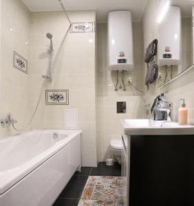a white bathroom with a tub and a sink at Apartment on Lukyanovska in Kyiv