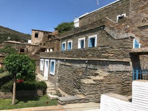 a stone house with white windows and a stone wall at Petra Traditional House in Episkopión