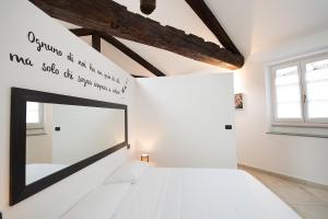 a white bedroom with a mirror on the wall at ReArduinoIvrea in Ivrea
