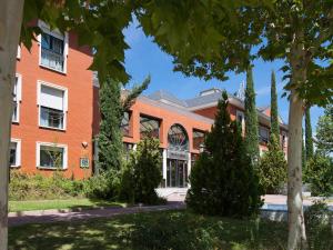 pomarańczowy ceglany budynek z drzewami przed nim w obiekcie Apartamentos TH La Florida w Madrycie