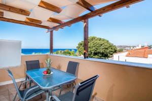 een tafel en stoelen op een balkon met uitzicht op de oceaan bij Filmar Hotel, Ixia, Rhodes in Ixia