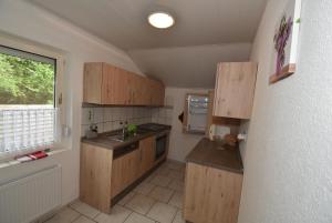 uma pequena cozinha com armários de madeira e uma janela em Fewo Mey em Greetsiel