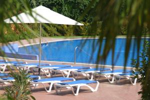 un grupo de sillas y una sombrilla junto a la piscina en Camping Joan Bungalow Park, en Cambrils