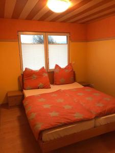 una camera da letto con un letto con pareti arancioni e due finestre di Ferienwohnung - Kurz a Sankt Wendel