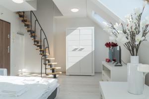 a white room with a spiral staircase and flowers at GUZ Apartamenty in Giżycko