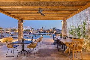 patio ze stołami i krzesłami oraz widokiem na wodę w obiekcie Portes Suites & Villas Mykonos w mieście Mykonos