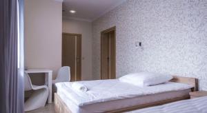 a white bedroom with a bed and a chair at Oleńka in Kutno