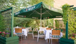 a patio with tables and chairs under a green umbrella at Hotel Union in Salzwedel