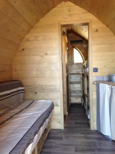 Cabaña de madera con cama y pasillo en La Colline Aux Cabanes en Espaly-Saint-Marcel