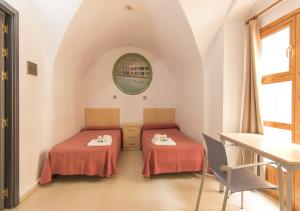 two beds in a room with a table at Albergue Inturjoven Córdoba in Córdoba