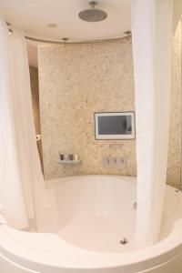 a bathroom with a tub with a tv on the wall at Le Monde Hotel in Edinburgh +37 photos