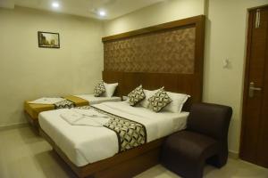 a hotel room with two beds and a chair at Olive Grand in Chennai