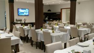 uma sala de jantar com mesas brancas e cadeiras brancas em Executivos Hotel em Cruz Alta
