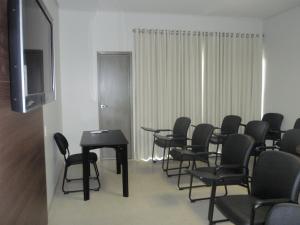 uma sala de conferências com cadeiras, uma mesa e uma televisão em Oásis Hotel em Araguaína