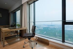 Yicheng Pazhou Poly World Trade Centre Apartment في قوانغتشو: مكتب مع مكتب وكرسي أمام نافذة
