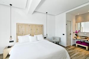 a bedroom with a large white bed and a desk at Portes Suites & Villas Mykonos in Mikonos