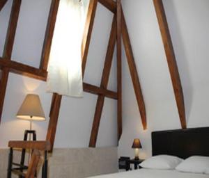 ペズナにあるLes Galeries de Beaulacの木製の天井とランプ付きのベッドが備わるベッドルーム1室が備わります。