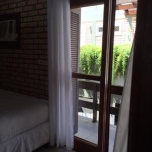 Habitación con puerta a un balcón con ventana en Bombinhas Quinta do Mar Complexo A, en Bombinhas