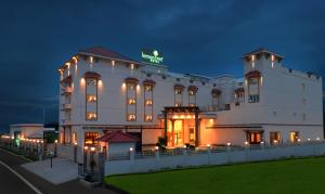 a large white building with lights on it at night at Lemon Tree Hotel Coimbatore in Coimbatore