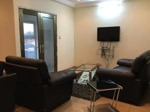 een woonkamer met 2 leren banken en een tv bij Julmarte in Lomé