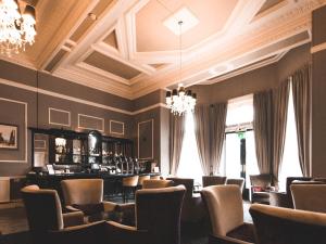 a bar in a restaurant with chairs and a chandelier at Great Victoria Hotel in Bradford