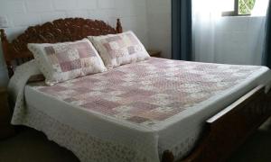 a bed with a pink and white quilt and pillows at Casa El Quisco Las Mandarinas in El Quisco