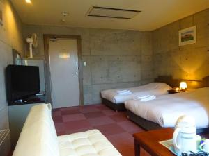 a hotel room with two beds and a flat screen tv at Hakodate Motomachi Hotel in Hakodate