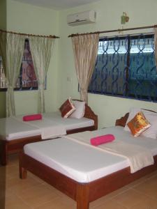 2 Betten in einem Zimmer mit 2 Fenstern in der Unterkunft Bun Kao Guesthouse in Siem Reap